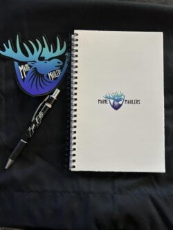 Maine Maulers branded notebook, pen, and sticker on a dark surface.