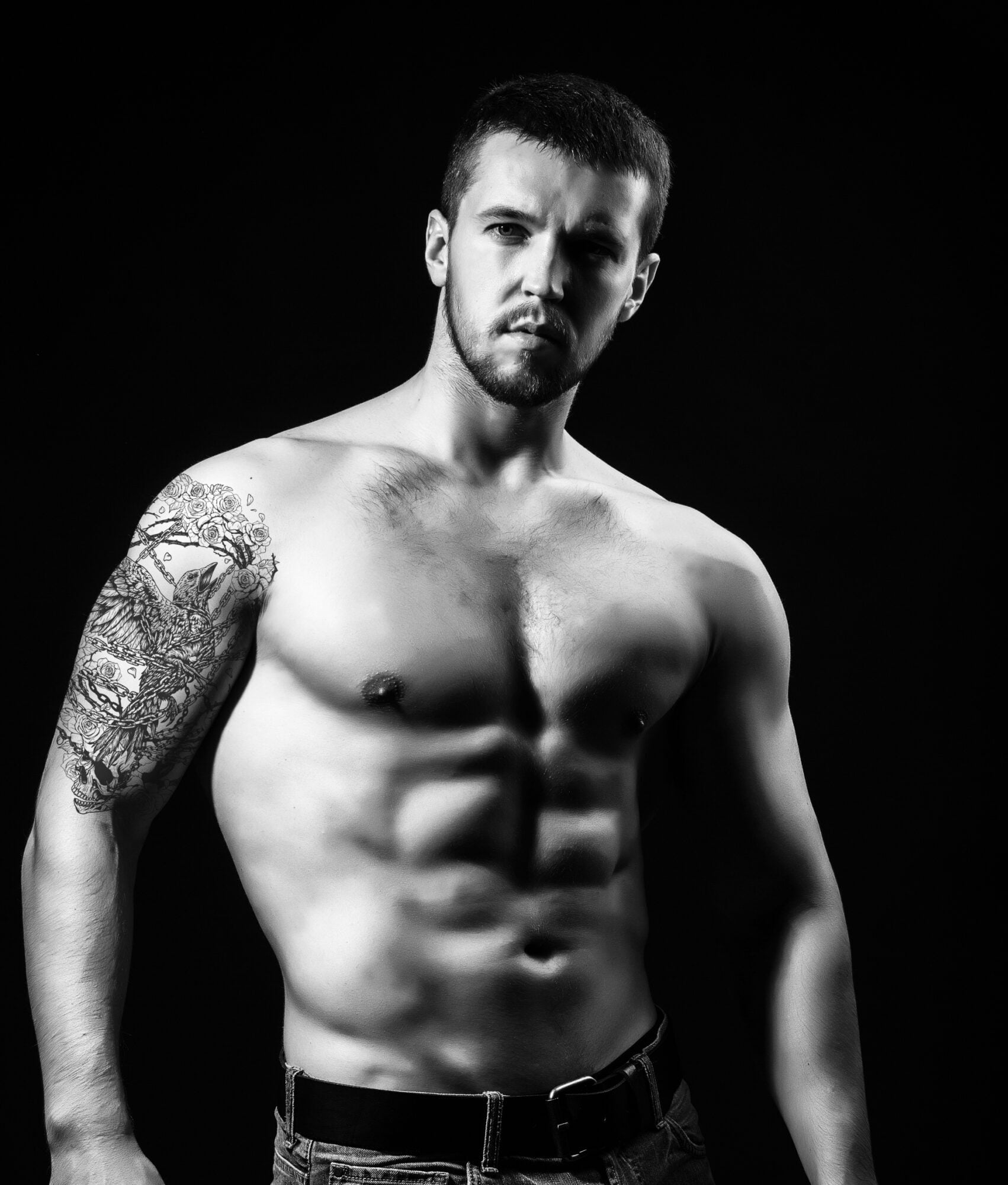 Muscular man in dramatic black and white portrait displaying confidence and striking physique.